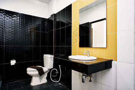 标准设施在黑墙和黄上装有黑色和黄陶瓷的小型旅馆或公寓装饰抽水马桶槽毛巾架和玻璃镜子洗浴盆家具白色的简单图片