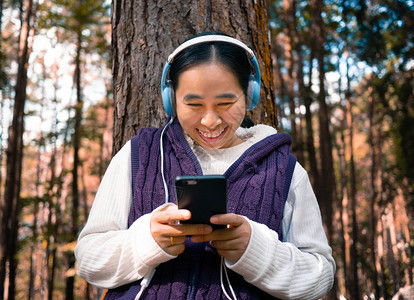 凉爽的小工具亚洲人在园艺技术和放松概念中亚洲年轻女孩听耳机音乐的亚裔青年女孩背景图片