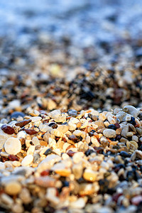 海岸的浅滩用狭窄太阳光照亮以色彩多的颜玩耍前景和背模糊近垂直的图像空间海滩石块被明光的太阳束反射而复制黄色的明亮模糊图片