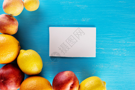 油桃子蓝色背景上的新鲜热带水果附有笔记纸从上方查看食物背景健康天然食品的概念蓝色背景上的新鲜热带水果附有笔记纸柑橘图片