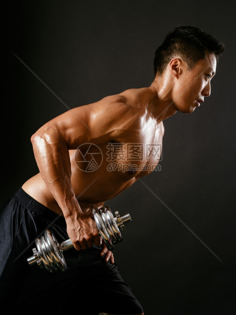 强的工作室照片来自亚裔男在黑暗背景上使用哑铃和做三轮赛跑的画面Focus就在手臂上垂直的图片