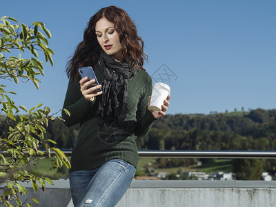应用程序淑女年轻红发青使用手机喝外卖杯咖啡的用她手机和咖啡杯喝红头发女青年取出图片