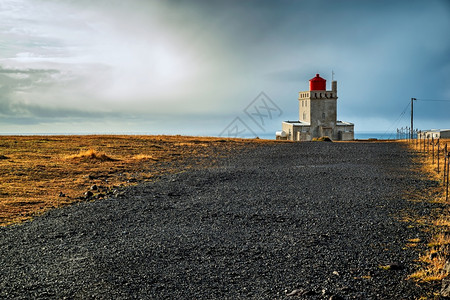 目的地灰蒙海日落时阴云的Dyrholaey灯塔冰岛日落时Dyrholaey灯塔图片
