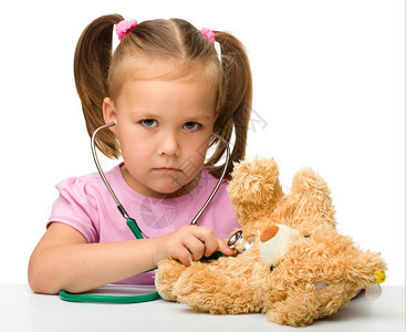 游戏超过小女孩正在用听诊器检查她的泰迪熊孤立在白色上面人类图片