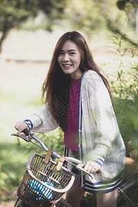 女在绿色公园骑着旧自行车的年轻女士们喜悦地在绿色公园中旅行循环图片