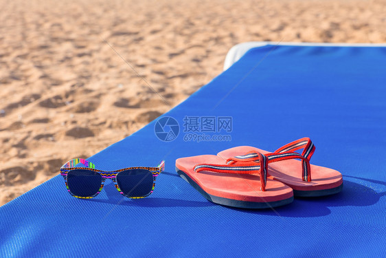 说谎葡萄牙晴天浴鞋和太阳墨镜在沙滩上蓝色的阳光下图片