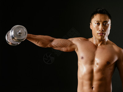 运动员萨姆纳斯胸部照片来自一位亚裔男在黑暗背景上使用哑铃和肩飞或横向翔的亚洲男运动图片