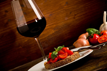樱桃Bruschetta美味的开胃菜和木制餐桌上红酒杯的照片反射图片
