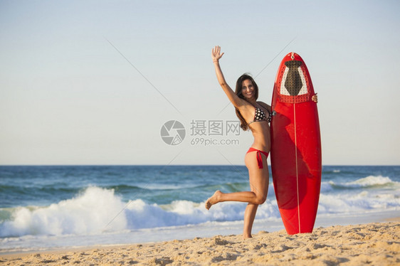 海滩上一个美丽的女孩抱着冲浪板图片