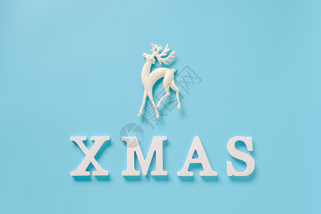 来自白色字母的文本圣诞节和蓝色背景上的圣诞装饰鹿玩具放置设计卡片邀请的模板节日复制蓝色的图片