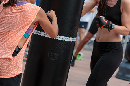 踢年轻女孩用黑色沙袋做健身和拳击锻炼年轻女孩用黑色沙袋做健身和拳击锻炼女孩们积极的图片