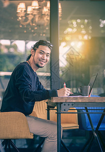 行政年青的亚洲自由职业者在家庭办公室工作手持计算机笔记本电脑牙笑脸肖像桌子图片