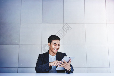 快乐的亚洲青年商业家从事数字板微笑和坐在工业厅作场所全拍摄服务台办公桌边的工作自己的男年轻图片