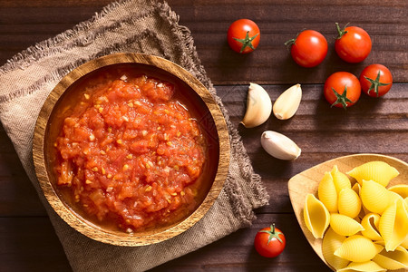 送达蔬菜由新鲜番茄大蒜干红树胶和盐制成的意大利传统马里纳拉或pomodoro番茄酱用配料和边面生粉的木碗做成用自然光在黑木上拍到图片