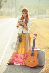 衣服在乡村公路上使用手机的美丽年轻嬉皮女青孩草吸引人的图片