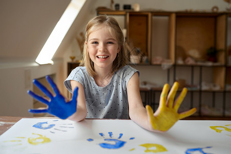 小女孩画她的手用古阿希孩子在艺术学校的习班上玩得开心年轻画家愉快的爱好乐童年小姑娘用古阿奇画她的手刷子人们画笔背景图片
