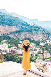 欧洲自由浪漫的意大利阿马尔菲海岸的意大利村庄背景中戴草帽的年轻女子背影图片