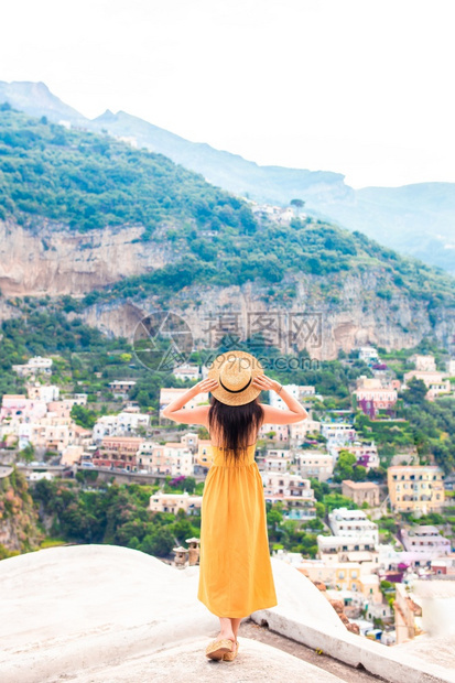欧洲自由浪漫的意大利阿马尔菲海岸的意大利村庄背景中戴草帽的年轻女子背影图片