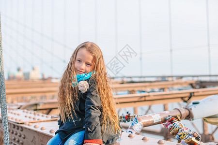 快乐的布鲁克林大桥上的漂亮女孩肖像纽约市美国曼哈顿坐在纽约布鲁克林大桥上的可爱小女孩历史时尚图片