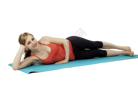 吸引人的漂亮锻炼年轻放松健身女年轻放松的健身女躺在她的蓝色垫子上白背景图片
