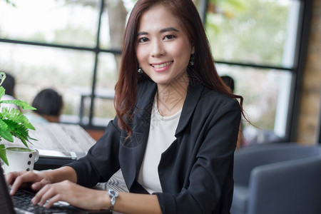 柔软的书成人使用笔记本的亚洲商业妇女与以工作软焦点为快乐微笑的商业妇女图片
