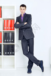 年轻商人在他的办公室中站着充满自信的青年商人英俊快乐员工图片