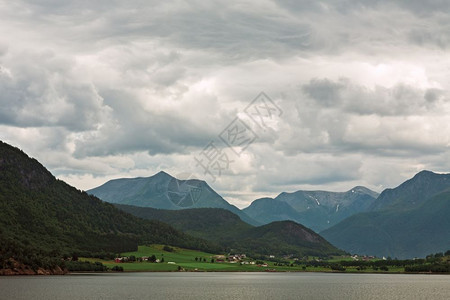 旅行海在多云的天空下挪威安道尔尼斯附近的Romsdalsfjorden沿线的小村庄和山脉挪威安道尔尼斯附近的沿线堪纳维亚图片