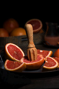 工作室红色的新鲜葡萄汁切片为在黑暗背景的盘子上制造新鲜果汁而准备柑橘图片