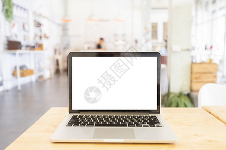 在咖啡店的木制桌子上用空白屏幕拍摄笔记本电脑的混装图象网络技术在线的图片