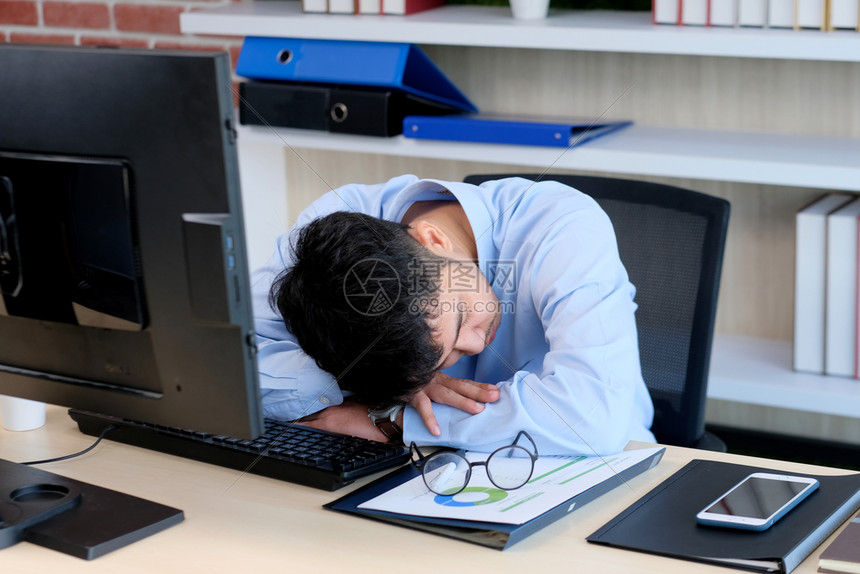 男人年轻商带着眼镜过量工作睡着觉创意临时工在作场所睡觉在办公室他感到很疲倦我非常兴奋人们晚的图片