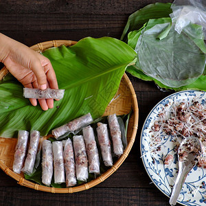 白饭越南的妇女在家里做春卷或香焦自制食物用肉填料米纸包装在绿叶背景上手滚越南鸡蛋卷受欢迎的图片