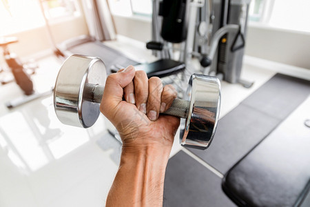 在健身房关紧一对手用左握着一个哑铃左手在健身房里锻炼和保健概念人类康运动图片