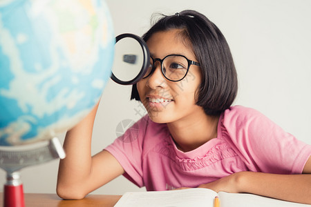 喜悦身戴眼镜的亚洲女孩在课堂上微笑并使用放大玻璃教育概念在课堂上乐趣快的图片