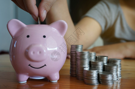 富有的妇女用手在小猪银行上打硬币投资女图片