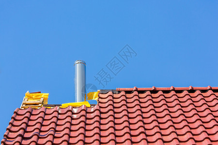 德尔登新的屋顶有砖和烟囱管对着蓝天排放阳光图片