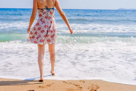 户外夏季在海滩上向走至边的妇女穿着赤脚双和足印在度假日海滩的足迹沿岸旅行晴天女图片