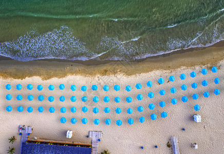 支撑闲暇户外海浪和蓝色雨伞的美丽小海滩空中最上层风景图片