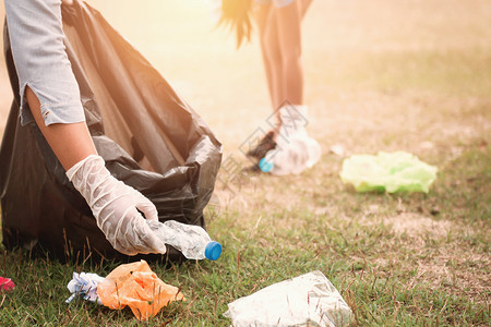 地球包妇女用手捡垃圾塑料在公园打扫自然图片