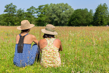 坐着请享用看到两个女人坐在一起盛开的草原上快乐图片