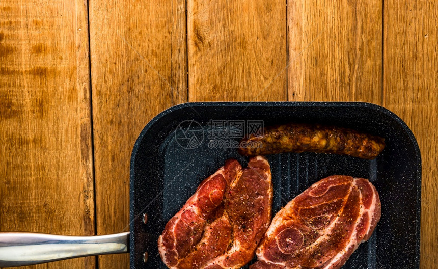 调味品鱼片在黑煎锅上木制桌子肉用于bbq顶视图复制空间烧烤概念上与调味料和熏香肠的猪排烹饪图片
