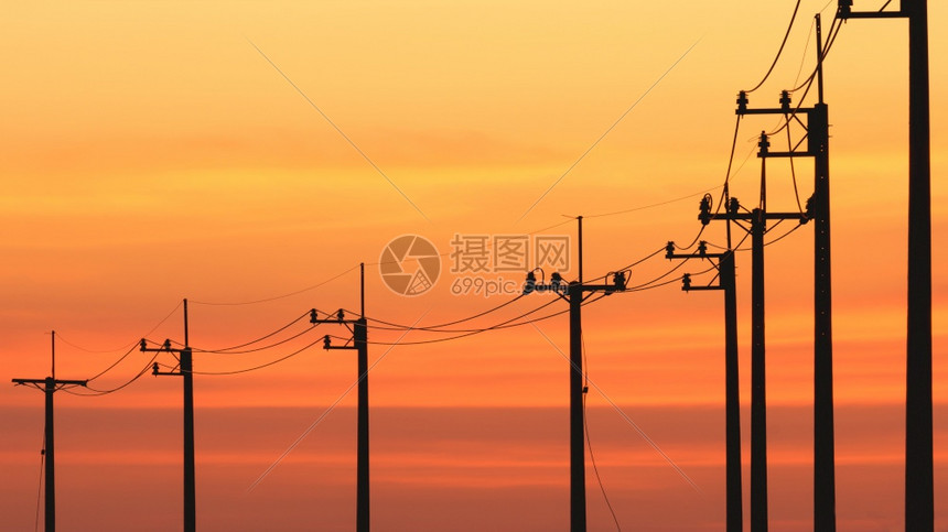 橙视线中许多电动极的轮光条与色彩多的日落天空背景相交黄昏行业图片