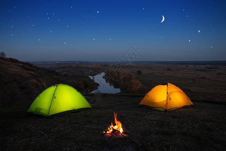 夜间河边露营两个发光帐篷图片