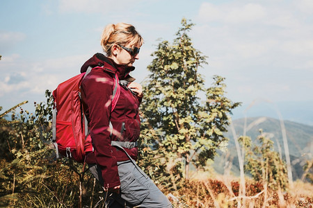 乐趣带着背包在山上徒步旅行的妇女与大自然相亲近度暑假的妇女在丛林和草之间行走的妇女户外水图片