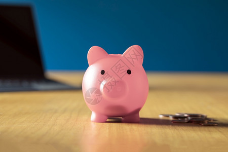 经济玩具家里木制办公桌上的粉红色存钱罐里面有一堆硬币储蓄投资业务和金融概念安全图片
