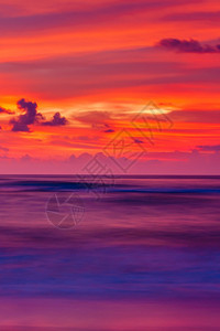 剥离日落时热带海滩的景色彩多的日落天空和波纹云层反射在海洋波浪表面和滩上长期运动模糊不清一种旅行图片