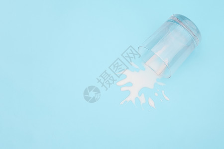 杯子放弃肮脏的溢出牛奶蓝色背景上加牛奶的翻转玻璃乳制品废弃概念复制空间顶视图溢出的牛奶图片