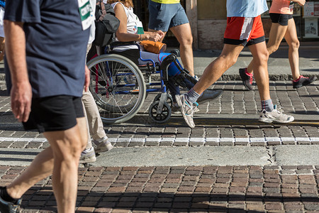 路男人在马拉松运动中在马拉松式轮椅上有一条受伤的女由RunnersWorld妇女帮助在马拉松式车轮椅上有一个受伤的男街道图片