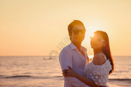 年轻快乐的亚裔夫妇在海滩上拥抱浪漫旅行蜜月渡假暑亚洲女和男在日落背景下手抱着户外海滨年轻的天空图片