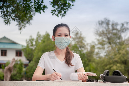 戴口罩的妇女坐在桌子上学习图片