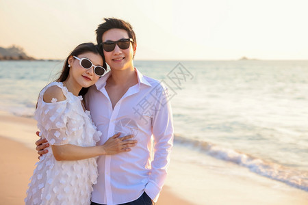 保持日落女孩年轻快乐的亚裔夫妇在海滩上拥抱浪漫旅行蜜月度假暑亚洲女和男手握拥抱户外图片